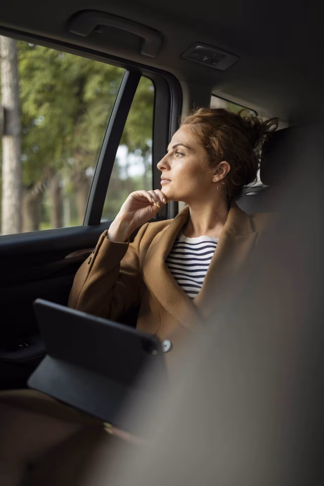 Viaggiatrice che osserva il panorama toscano dal finestrino di un'auto.