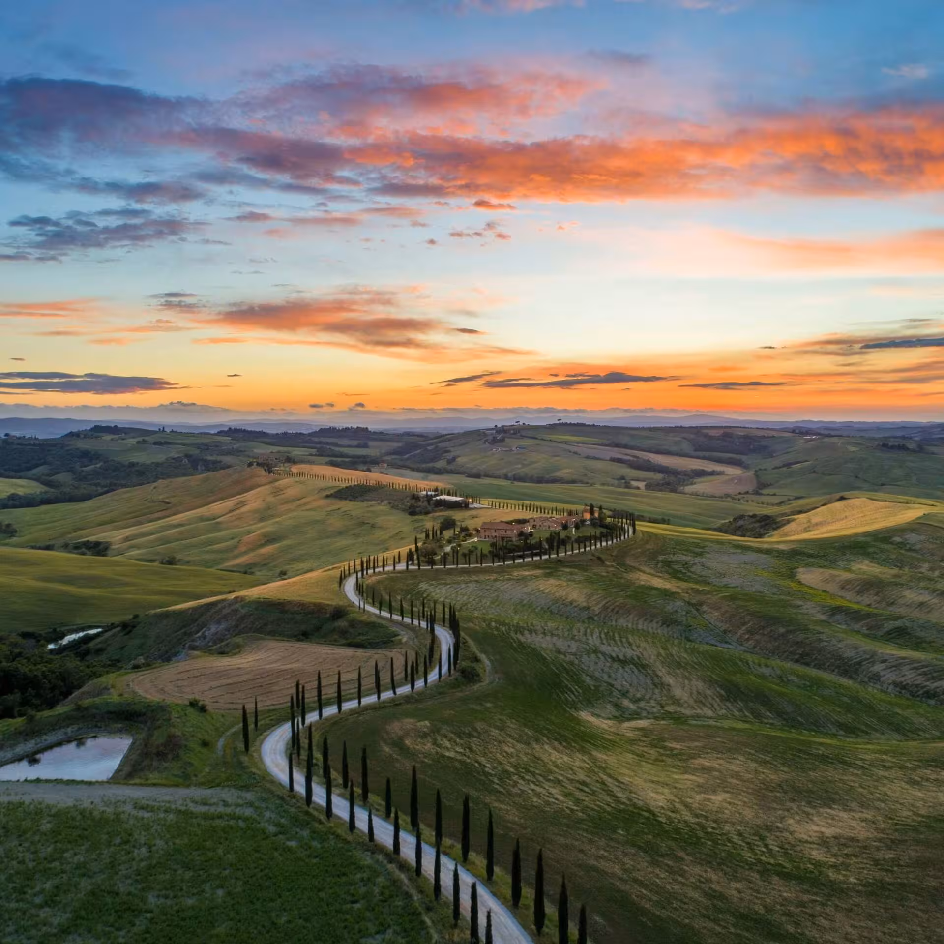 Strada panoramica tra le colline della Val d'Orcia alle luci del tramonto.