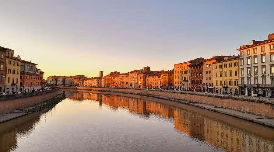 Riflessi dei palazzi storici sull'Arno a Pisa durante l'ora d'oro.