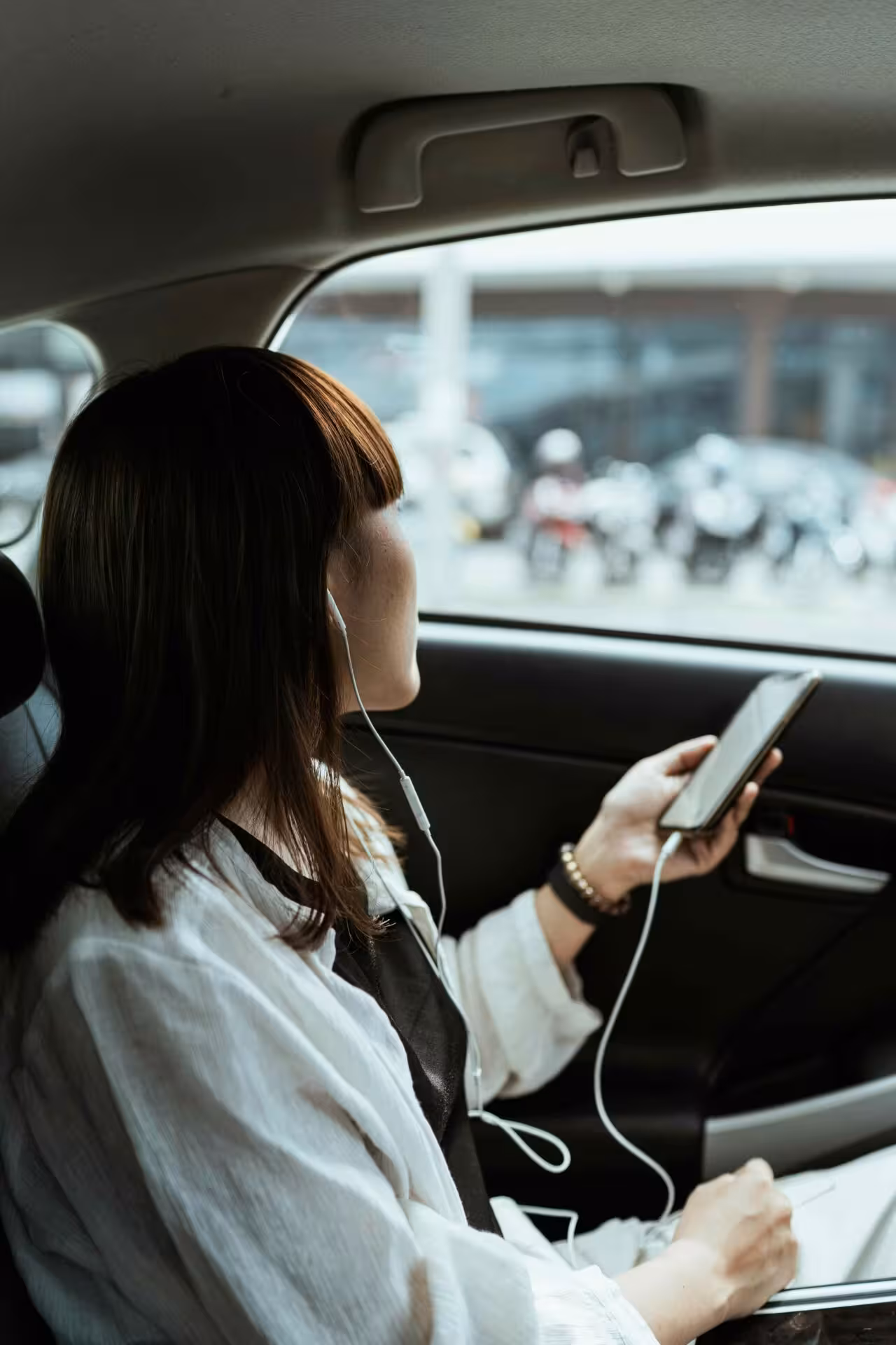 Giovane donna che utilizza lo smartphone nel sedile posteriore di un'auto NCC