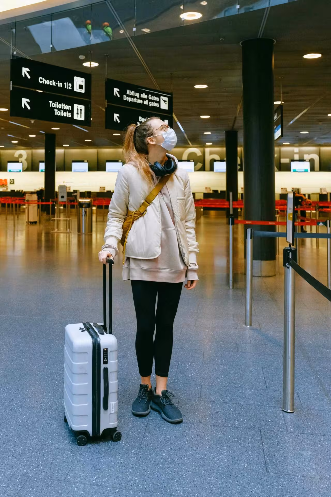 Viaggiatrice con trolley in attesa nell'area partenze di un aeroporto.